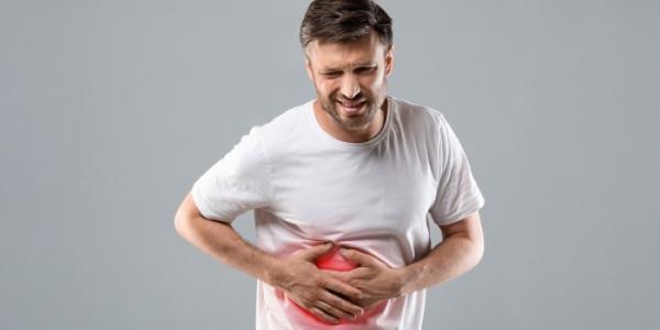 Un paciente pone sus manos en su abdomen 