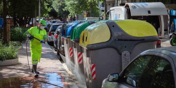Operario de limpieza del servicio municipal desinfecta un contenedor amarillo de residuos