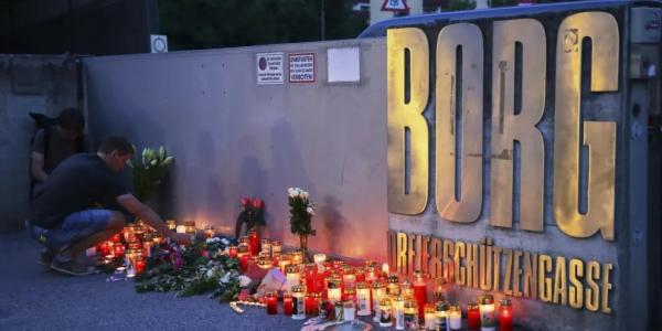 Dos jóvenes dejan velas en la puerta del instituto de Graz.
