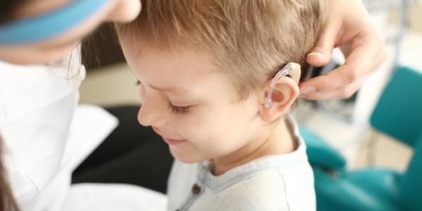 Una doctora coloca el audífono de un implante coclear a una niña 