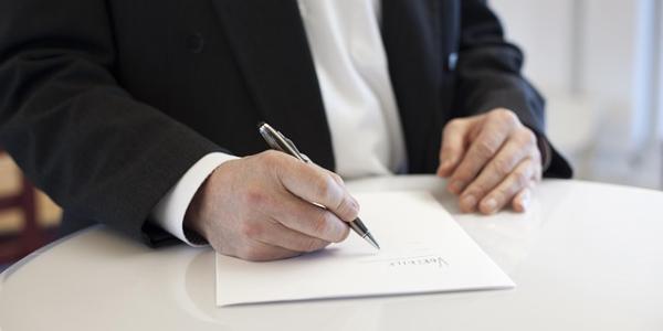 Manos de un señor firmando herencias