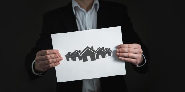 Infografía de un chico sosteniendo un cartel con varias casas dibujadas