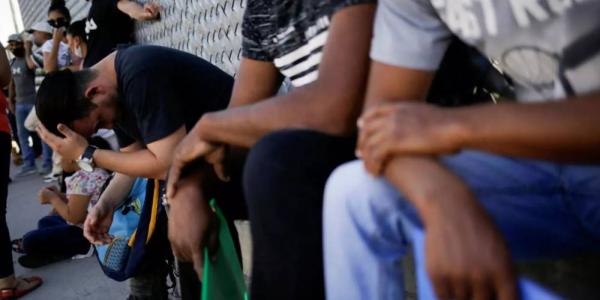 Migrantes del programa 'Permanecer en México' hacen fila fuera de las instalaciones del Instituto Nacional de Migración (INM) para renovar su permiso de permanencia legal en México, en espera de su audiencia de migración en Estados Unidos. Imagen en Ciudad Juárez, México, el 8 de julio de 2020. © Jose Luis González / Reuters