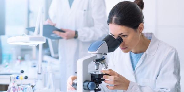 Una científica mirando por un microscopio 