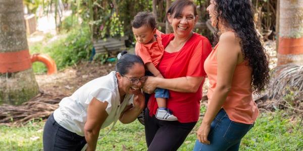 Tres madres sonriendo con un bebé en brazos