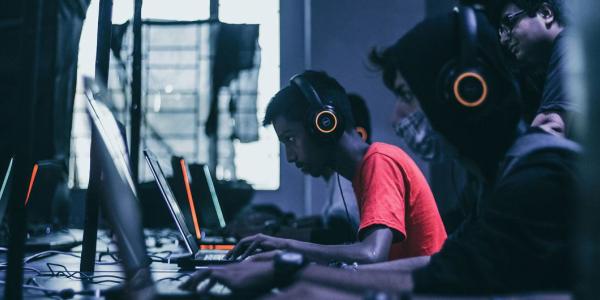 Dos jugadores juegan en ordenadores portátiles uno al lado del otro.