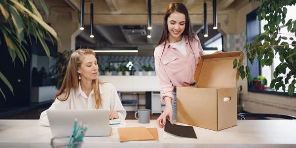 Dos chicas en la oficina recogiendo sus cosas en cajas