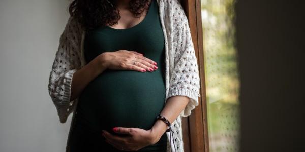 Mujer embarazada con sus manos posadas en la tripa