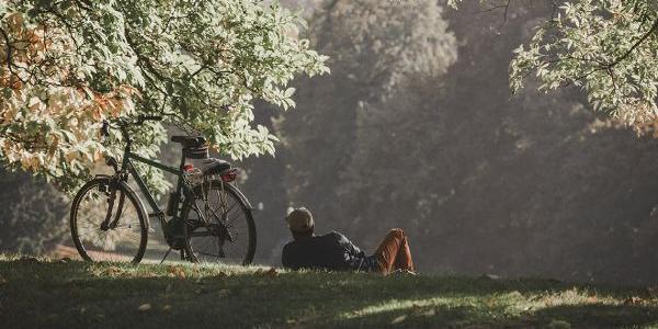 Señor descansando en el campo tumbado tras un paseo en bicicleta