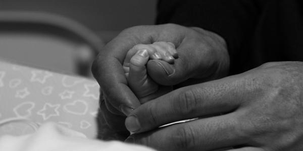 Manos de unos padres con su bebé recién nacido