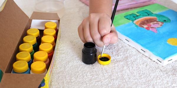 Mano de un niño pintando con acuarelas