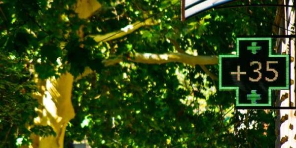 Una cruz verde de una farmacia indica una temperatura de 35 grados