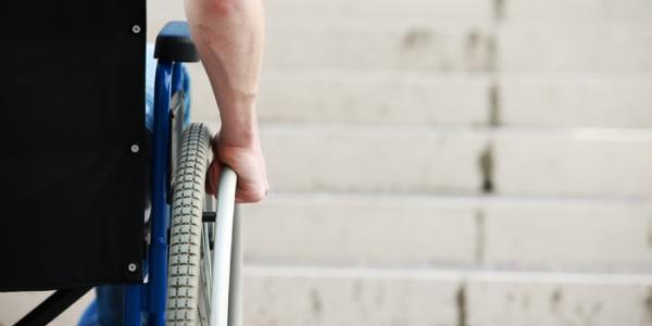 Persona en silla de ruedas ante una escalera 