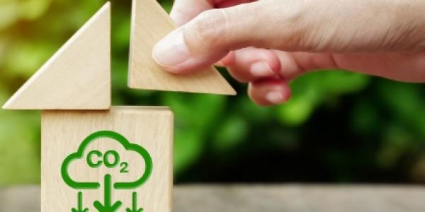 Mano de una persona encajando piezas de un puzzle con el símbolo de CO2