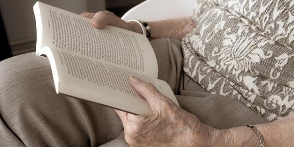 Manos de una mujer jubilada leyendo un libro