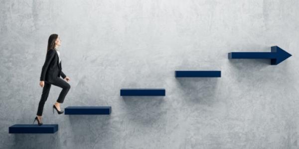 Mujer empresaria subiendo los peldaños de una escalera en la pared