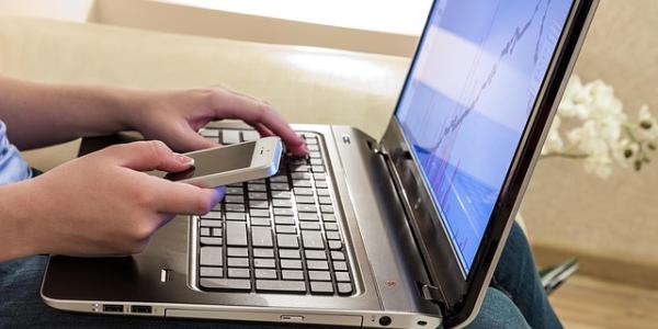 Manos de una persona en teletrabajo con su portátil y el móvil