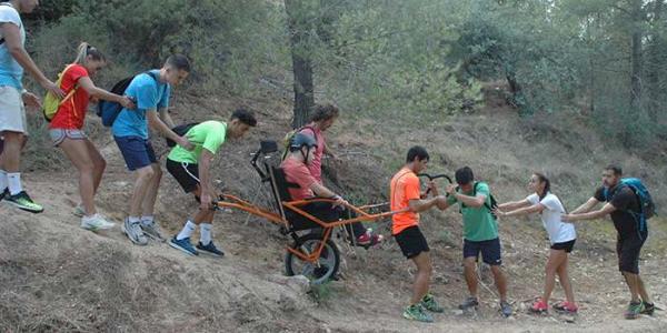 Un grupo de senderistas ayuda a una persona con discapacidad en una silla adaptada 