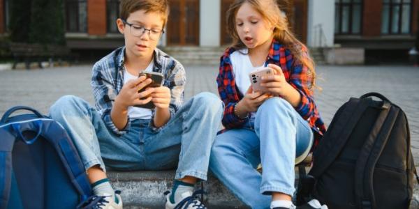 Niños sentados mirando el móvil