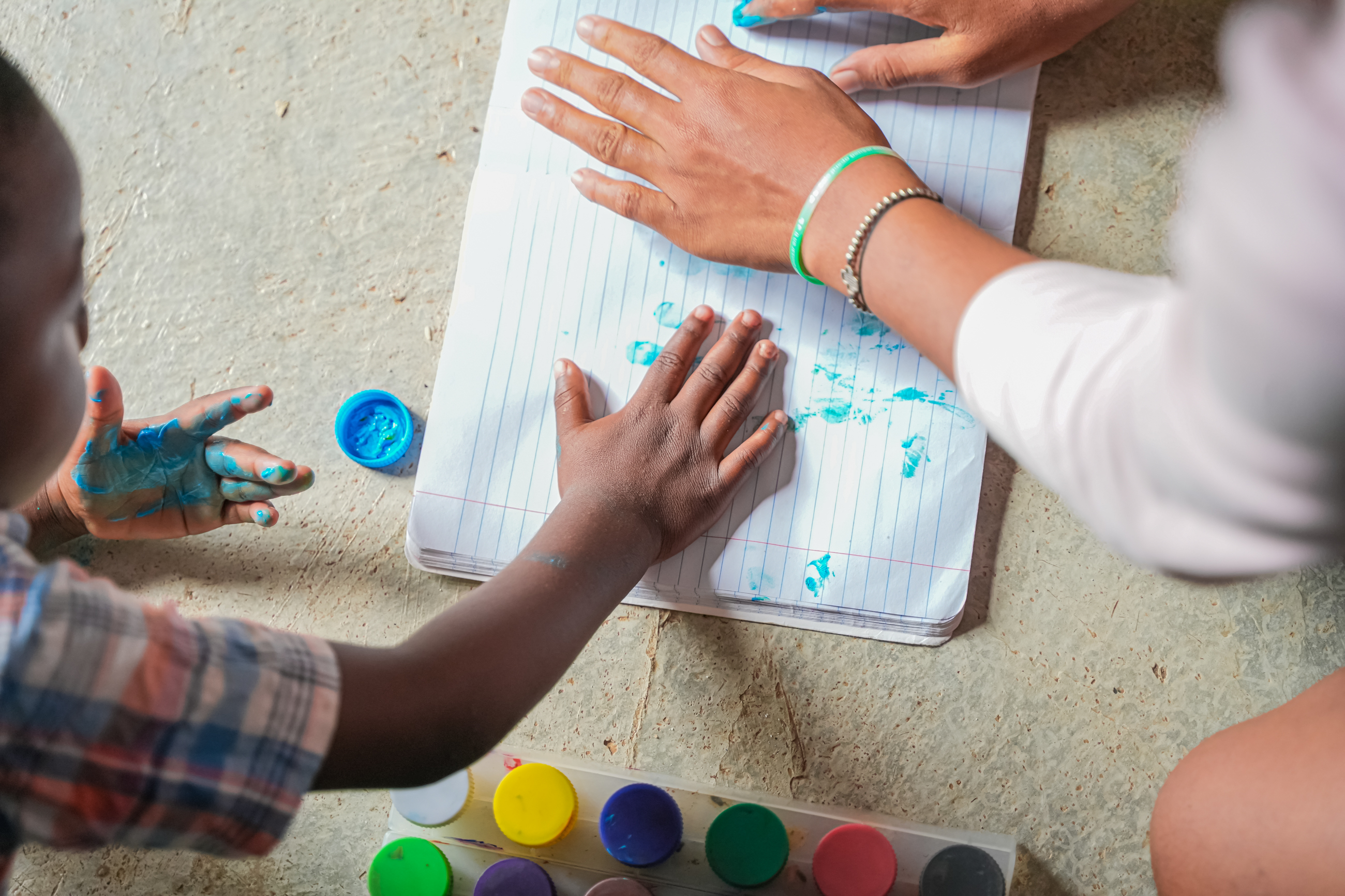 Manos de un niño y su educadora /  100 mil pisos para jugar 