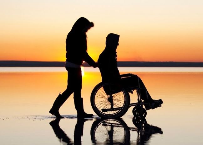 Una persona en silla de ruedas con un asistente personal 