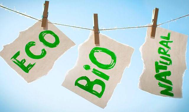 Infografía que muestra etiquetas de Eco, Bio y Natural, tendidas en una cuerda de tender ropa