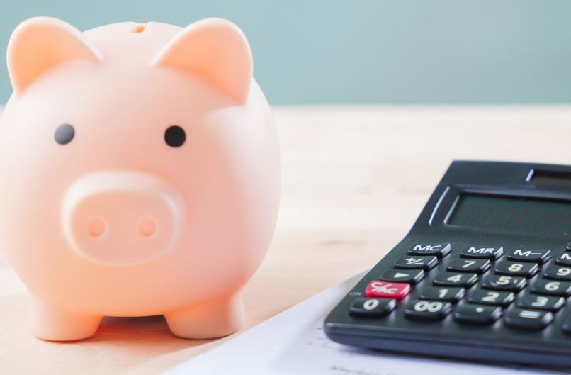 Imagen de una hucha con forma de cerdito y una calculadora