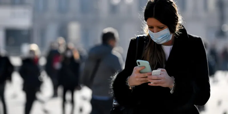 Mujer mirando un mensaje con mascarilla