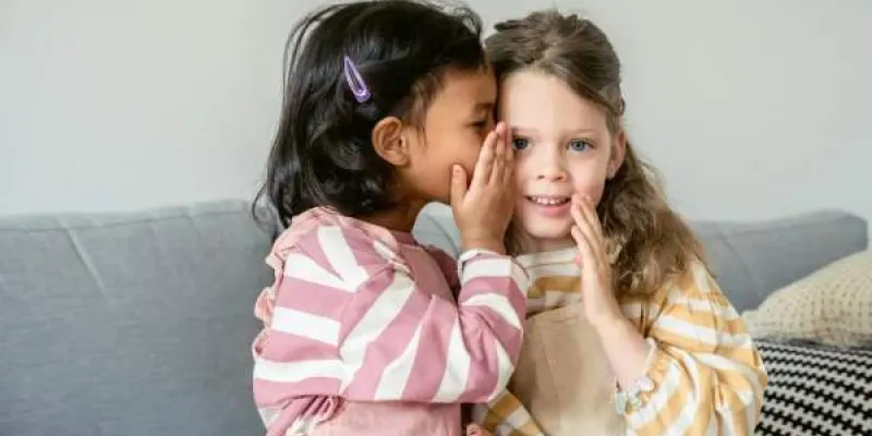 Dos niñas contándose un secreto al oído