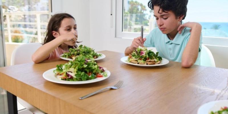 Dos menores comen comida vegetariana 