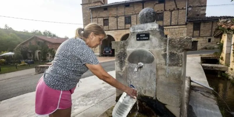 Una vecina llena una garrafa en la fuente del pueblo, a la que tienen que acudir para beber de agua potable