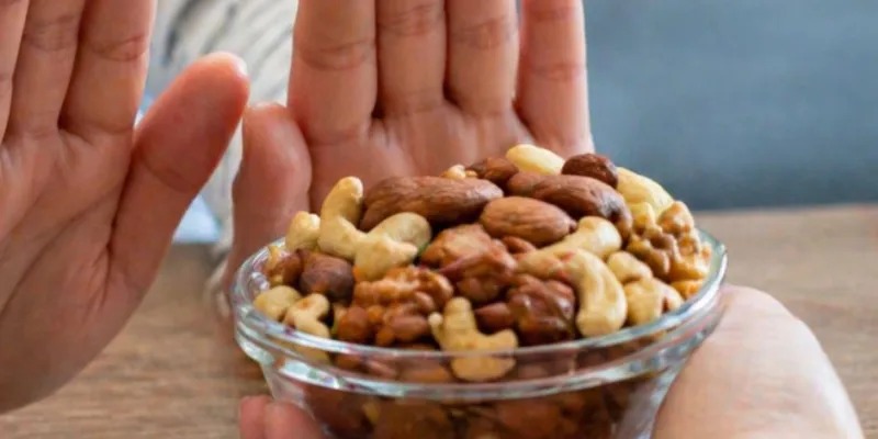 Manos de una persona apartando un bol de frutos secos