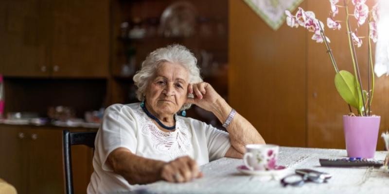 Una mujer mayor sentada junto a la mesa de su casa 