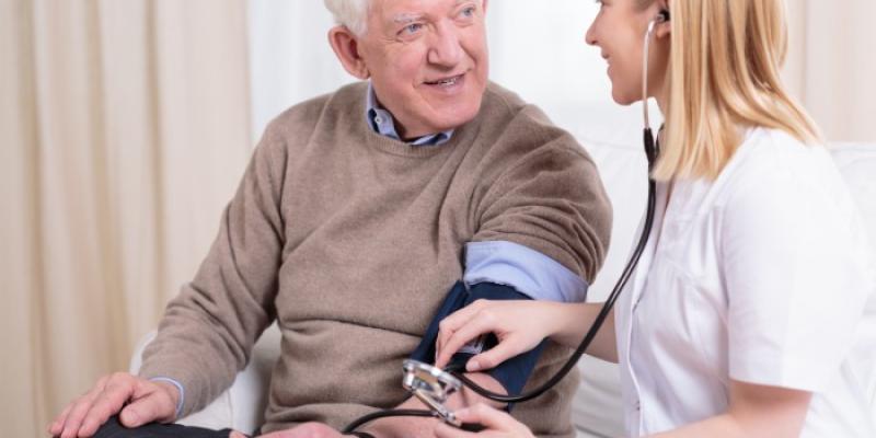 Cuidadora controla la presión arterial a un señor mayor