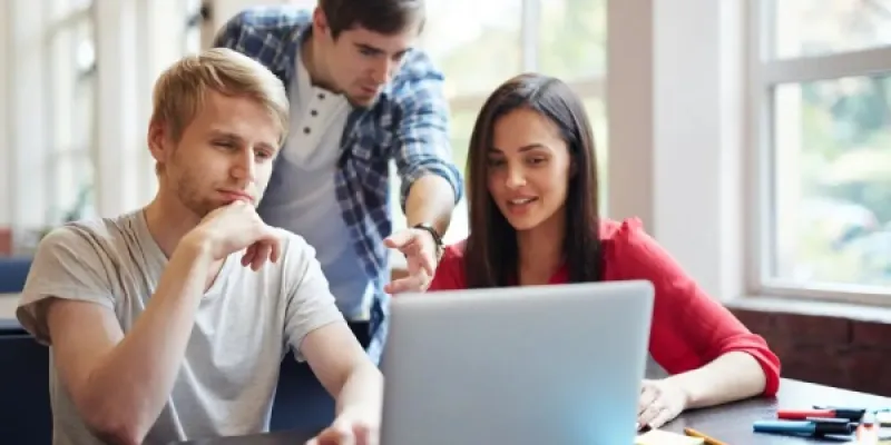 Jóvenes consultando las nuevas becas y ayudas en un portátil
