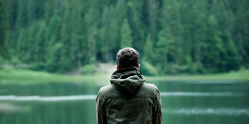 Hombre pensativo frente a un lago