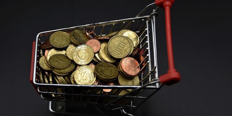 Carrito de la compra en miniatura lleno de monedas 