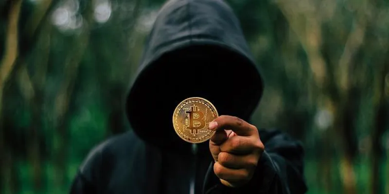 Un joven encapuchado sujeta un Bitcoin 