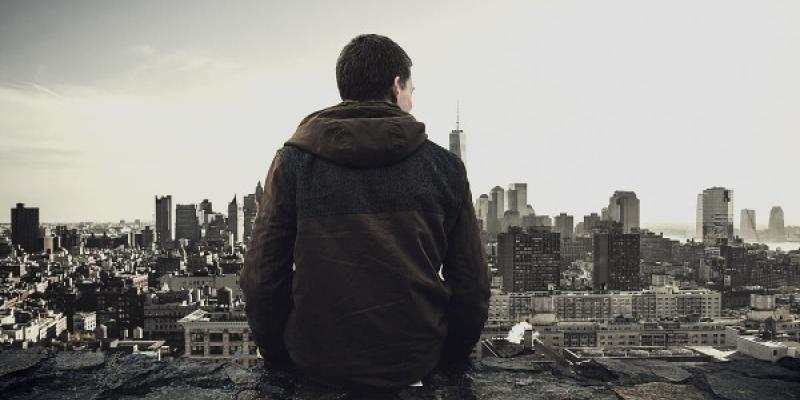 Chico de espaldas mirando una ciudad en blanco y negro