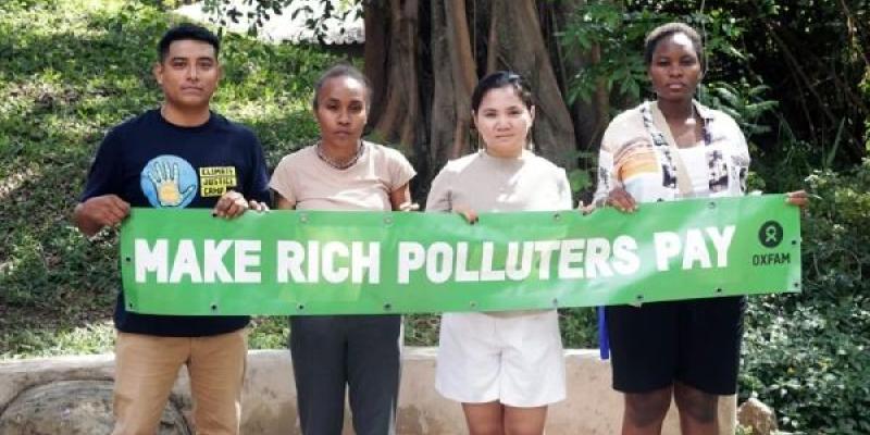 Activistas climáticos con una pancarta que pide gravar a los grandes contaminantes. 