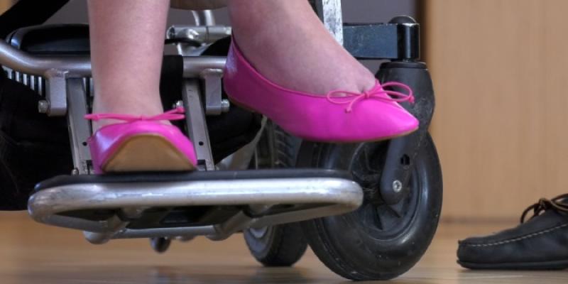 Una mujer con ELA apoya sus pies en una silla de ruedas
