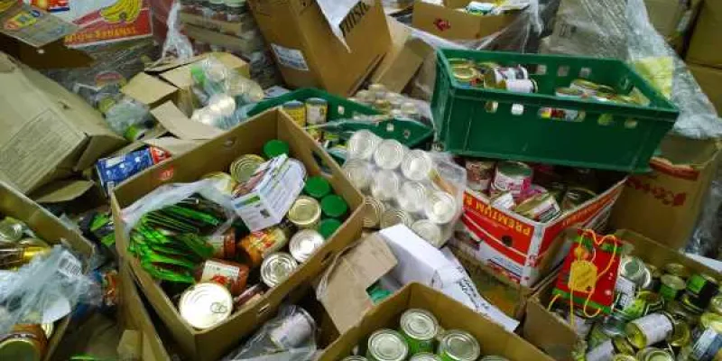 Cajas de cartón con alimentos enlatados en latas en suelo.