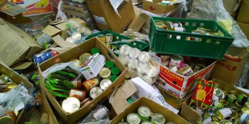 Cajas de cartón con alimentos enlatados en latas en suelo.