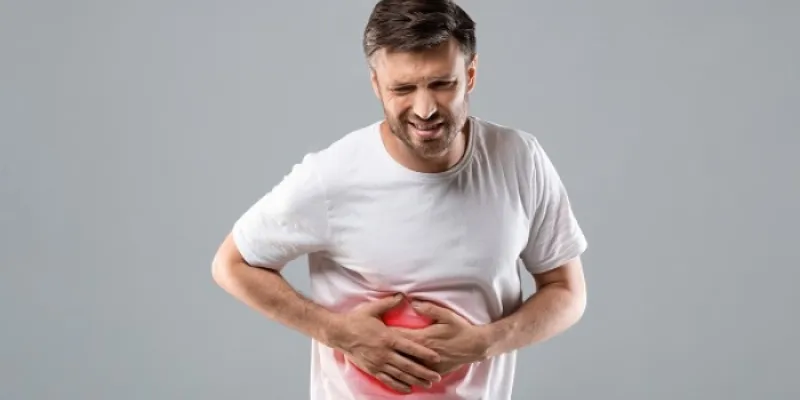 Un paciente pone sus manos en su abdomen 