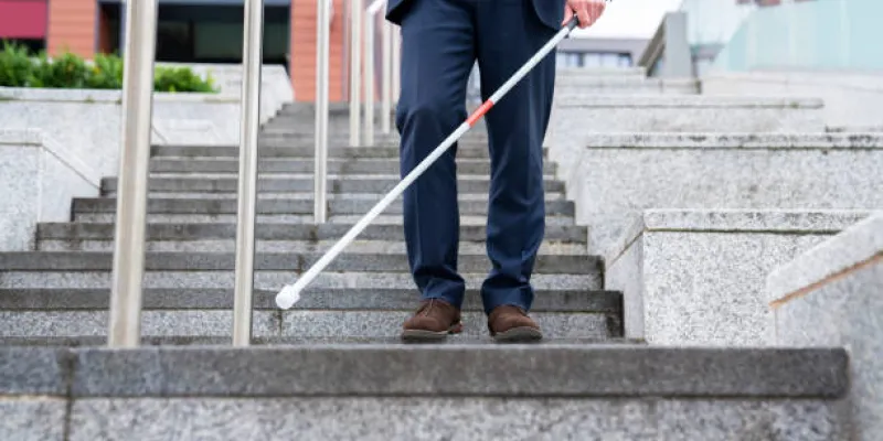Una persona con discapacidad visual usando bastón de ciego para las escaleras