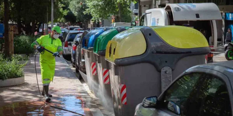 Operario de limpieza del servicio municipal desinfecta un contenedor amarillo de residuos