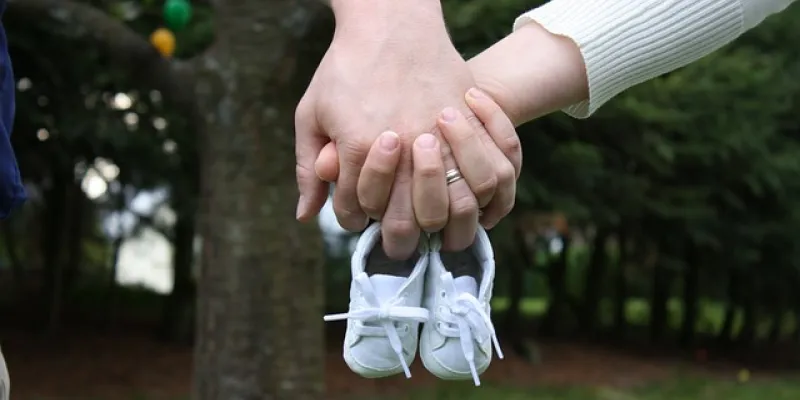 Manos de dos personas sosteniendo unos zapatos de bebé