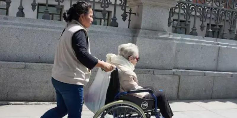 Mujer extranjera cuidado de una persona dependiente en silla de ruedas