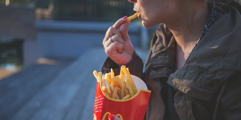Persona comiendo patatas fritas de una conocida cadena de fast food