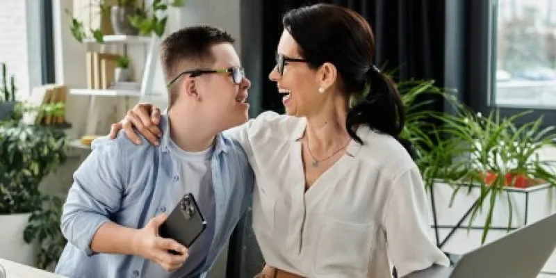 Un chico con discapacidad riendo con su mentora empresarial